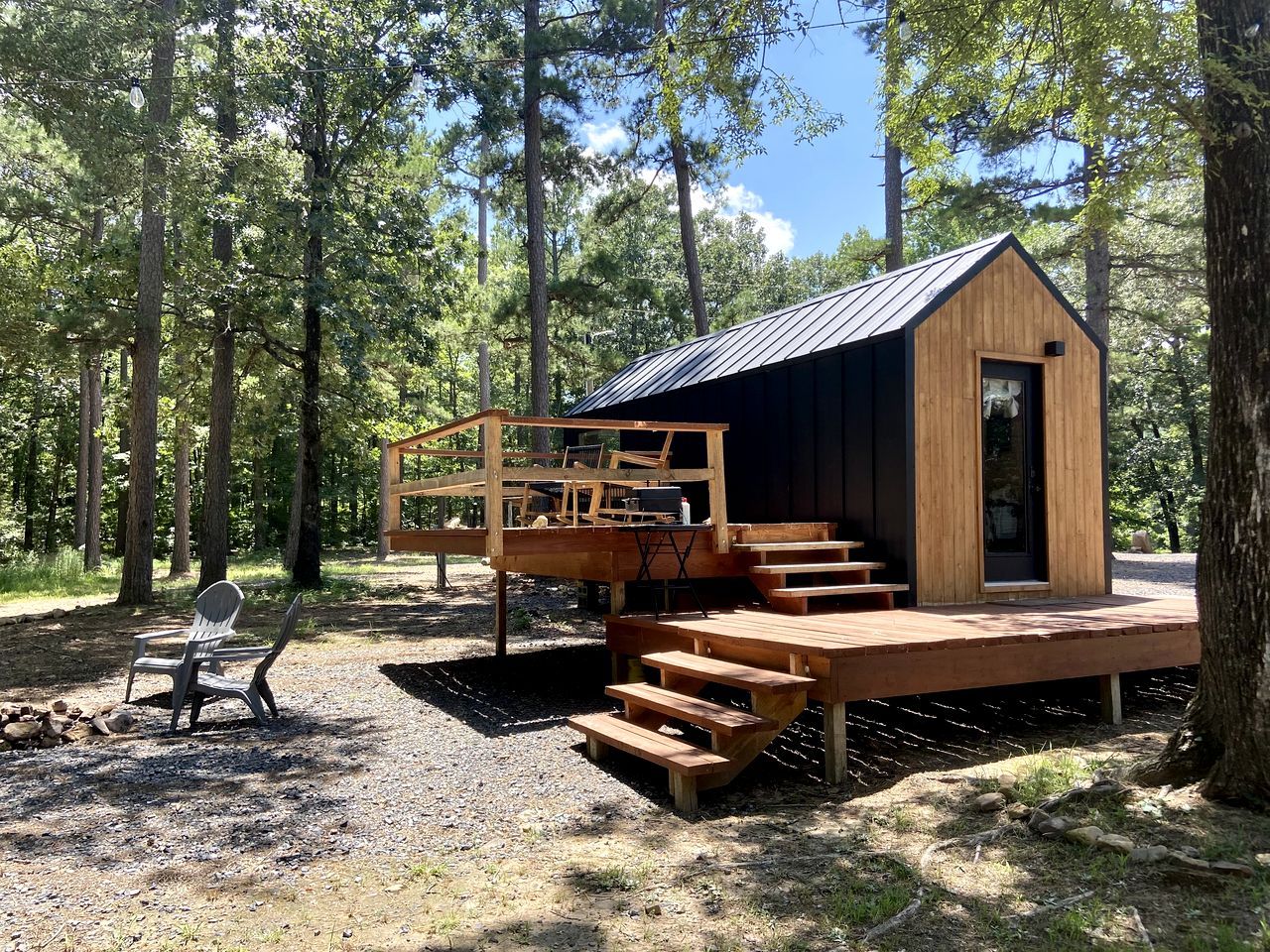 A wooden cabin with a deck, outdoor seating, and a small porch.