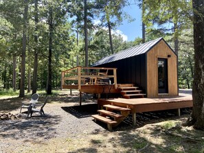 Une cabane en bois dotée d’une terrasse, d’un espace salon extérieur et d’un petit porche.