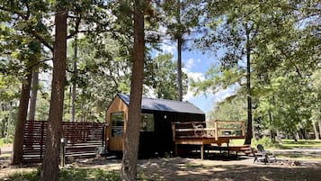 Un rustico chalet con veranda in legno e piccolo portico, immerso tra gli alberi.
