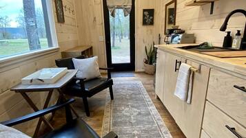 A cozy cabin interior with a dining area, a kitchen with a sink and cabinets, and a view through a door.