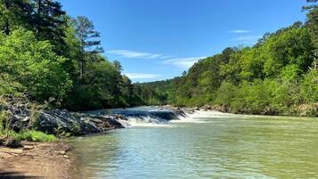 A river flowing through a forested area with clear skies.
