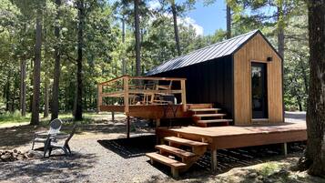 Una cabaña de madera con un porche, mobiliario exterior y una pequeña terraza.