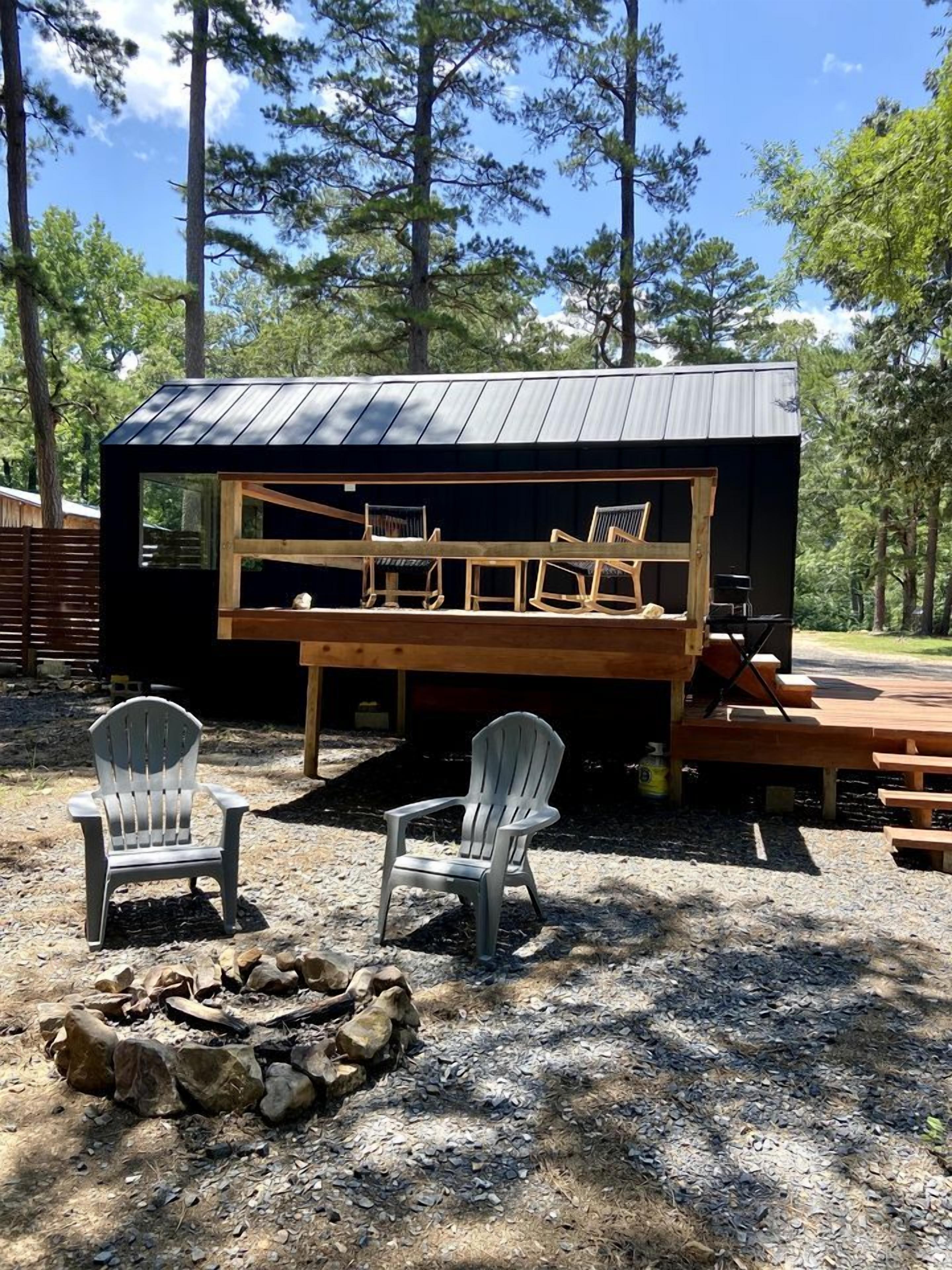 Une cabane avec une terrasse, deux fauteuils Adirondack et un foyer extérieur.