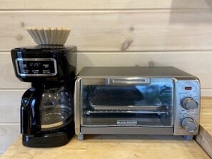 A coffee maker and a toaster oven on a wooden surface.