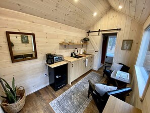 Une cuisine compacte avec des meubles en bois, un évier et un petit coin repas comprenant une chaise et une table.