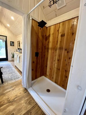 Une douche avec des panneaux en bois, une baignoire blanche et un drain apparent.