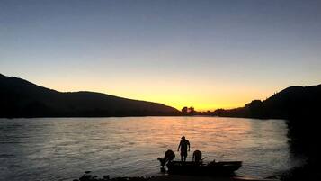 A river at sunset with people and a boat on the shore.