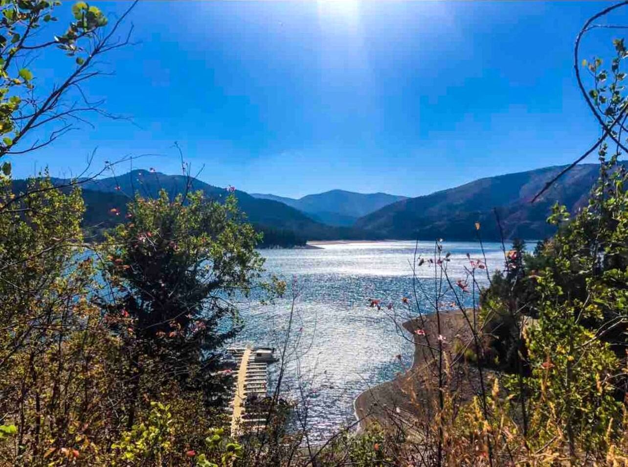 A lake with mountains in the background, surrounded by trees.