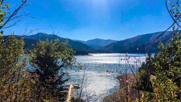 A lake with mountains in the background, surrounded by trees.