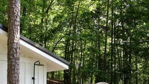 A hot tub with a wooden barrel structure in a forested area. - Off-grid Tree House Suitable for Four in Alabama (Scottsboro)