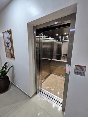 An elevator with a metallic interior, a control panel with a red light, and a safety sign on the wall. - HOTEL BELLAVISTA (Paulo Afonso)