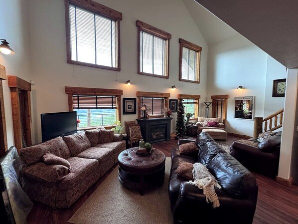 A spacious living room with a fireplace, multiple seating areas, and large windows.