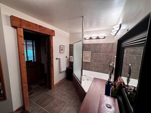 A bathroom with a bathtub, a shower, a vanity with a mirror, and a towel rack.