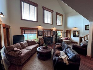 A spacious living room with a fireplace, multiple seating areas, and large windows.