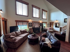A spacious living room with a fireplace, multiple seating areas, and large windows.