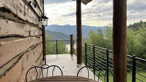 Une terrasse en bois avec une table et des chaises, offrant une vue sur un paysage montagneux.