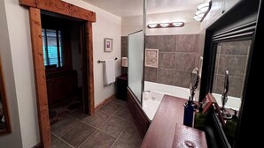 Une salle de bain équipée d’une baignoire, d’une douche, d’un meuble-lavabo avec un miroir et d’un porte-serviettes.