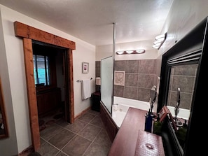 Een badkamer met een badkuip, douche, wastafel met spiegel en een handdoekrek.