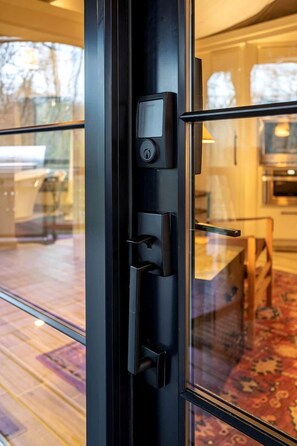 Ein modernes Interieur mit Glastür, Kartenleser und Blick auf einen Essbereich mit gemustertem Teppich.