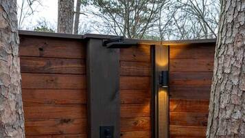 Une porte en bois dotée d’une poignée en métal et d’un trou de serrure, intégrée à une structure en bois surmontée d’une terrasse en bois.