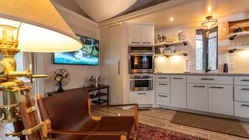 A modern kitchen with white cabinets, stainless steel appliances, and a red patterned rug.