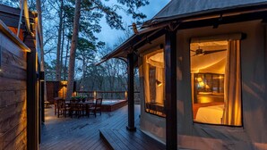 Une terrasse en bois avec un jacuzzi, un coin repas et une chambre avec une fenêtre donnant sur la terrasse.