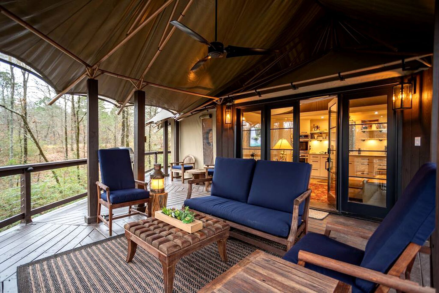 A covered outdoor deck with seating, a table, and a view of the interior.
