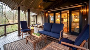 Une terrasse extérieure couverte, aménagée avec des sièges et une table, et offrant une vue sur l’intérieur.