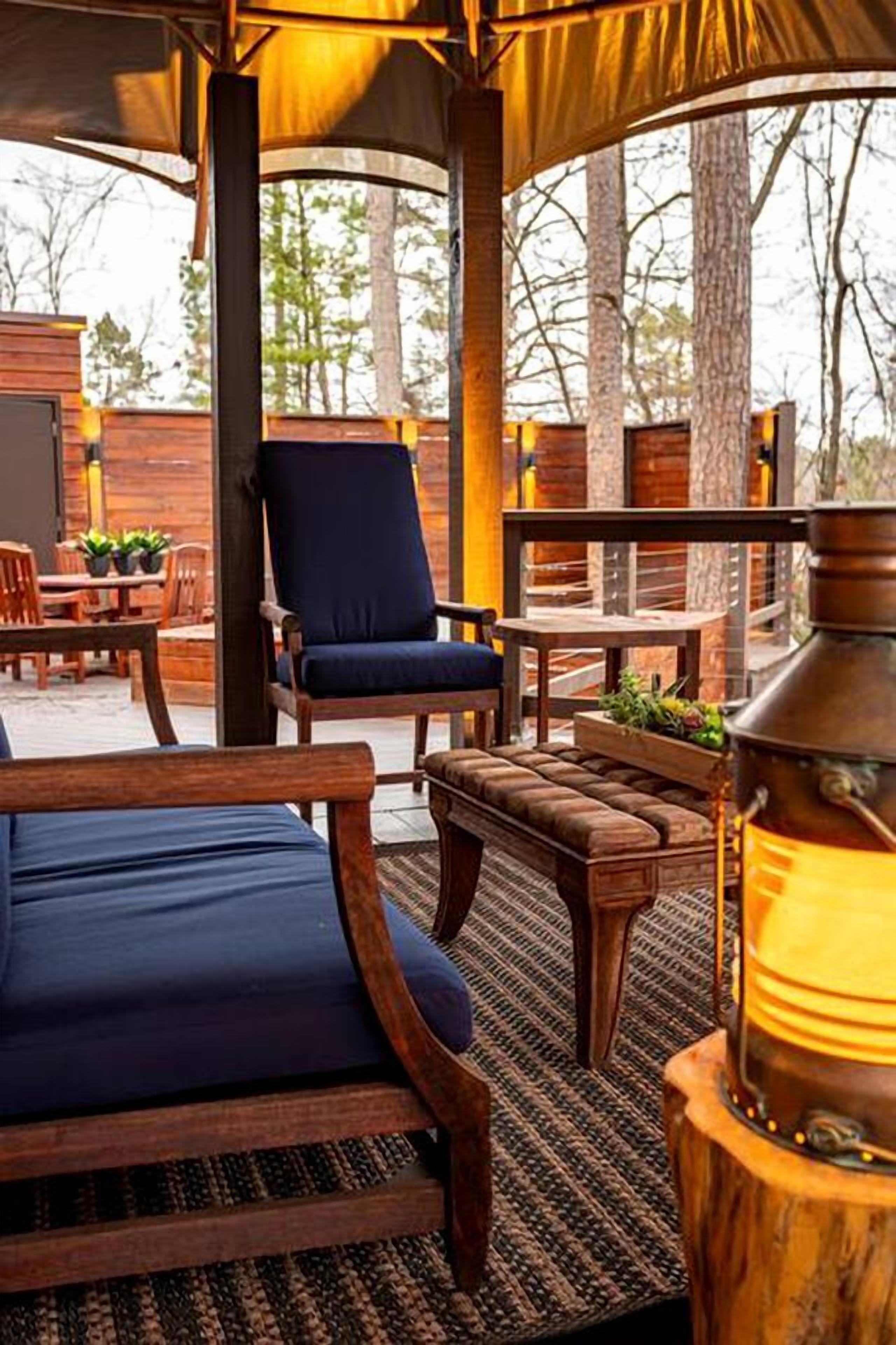 Un espace extérieur aménagé avec du mobilier en bois, un fauteuil rembourré et une table.