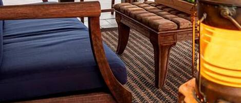 Un área de estar al aire libre con muebles de madera, una silla acolchada y una mesa.