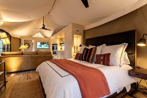 Una habitación de hotel moderna con una cama grande, un sofá, un televisor y una kitchenette.