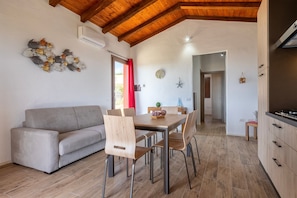 Une cuisine moderne avec des meubles en bois, une table à manger avec des chaises et un canapé gris.
