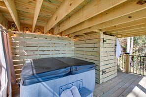 Un chalet en bois avec un jacuzzi, des poutres apparentes et un balcon.