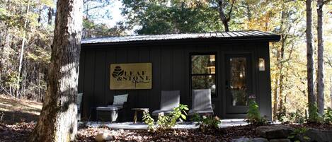 Un petit bâtiment avec une enseigne indiquant « Leaf & Stone Spa » et deux chaises en osier à l’extérieur.
