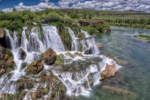 A waterfall with multiple cascades over rocks, surrounded by greenery and a river. - Charming Swan Valley Cottage with Clubhouse Access Near Palisades Lake, Idaho (Irwin)