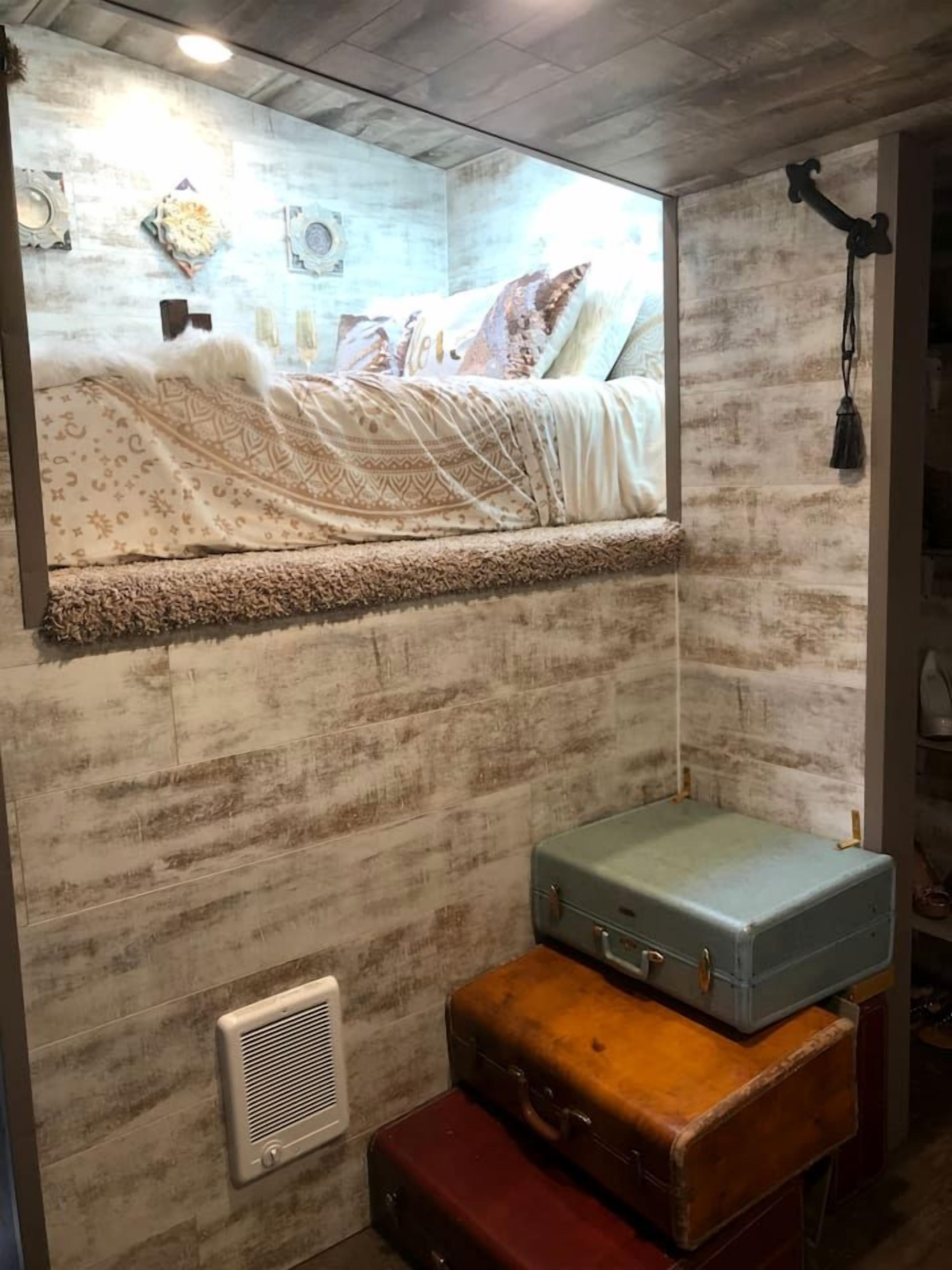 Ein Zimmer mit Bett, Spiegel, Heizkörper und Koffer.