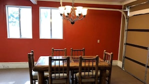 A dining area with a wooden table and chairs, a chandelier, and a garage door. - Beautiful Tiny House with Wrap-Around Deck and Skylight for a Romantic Escape in Irwin, Idaho (Irwin)