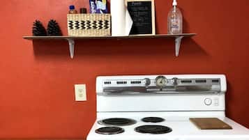 A kitchen with a white stove, wooden table, and red walls.