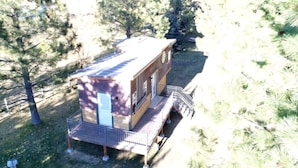 A small cabin with a deck, surrounded by trees. - Beautiful Tiny House with Wrap-Around Deck and Skylight for a Romantic Escape in Irwin, Idaho (Irwin)