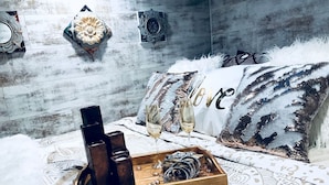 A bed with a patterned bedspread, a tray with bottles and glasses, and decorative pillows. - Beautiful Tiny House with Wrap-Around Deck and Skylight for a Romantic Escape in Irwin, Idaho (Irwin)