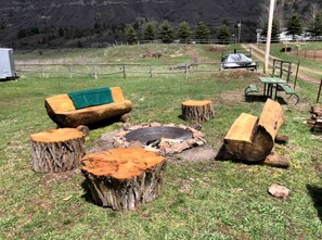 A rustic outdoor seating area with a fire pit, wooden benches, and a picnic table. - Beautiful Tiny House with Wrap-Around Deck and Skylight for a Romantic Escape in Irwin, Idaho (Irwin)
