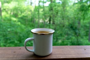 A white ceramic mug with a handle on a wooden surface. - Stunning Tented Cabin with Fire Pit in Des Moines, Iowa (Des Moines)