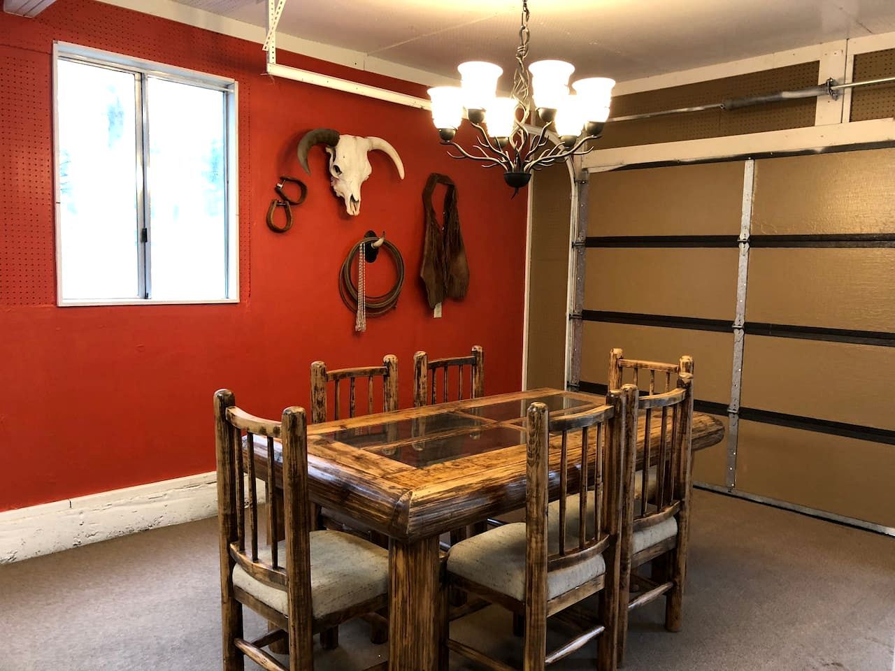 Ein Essbereich mit Holztisch und Stühlen, einer Kronleuchter und einer roten Wand mit Schädelverzierung.