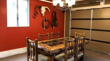Ein Essbereich mit Holztisch und Stühlen, einer Kronleuchter und einer roten Wand mit Schädelverzierung.