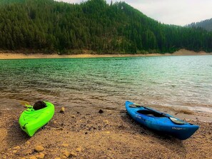 A calm lake with kayaks on the shore.