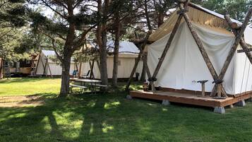 A campsite with tents, a picnic table, and a wooden deck.