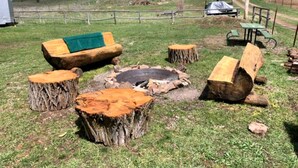 A rustic outdoor seating area with a fire pit, wooden benches, and a picnic table. - Pet-Friendly Safari Tent Glamping in Swan Valley, Idaho near Jackson Hole (Irwin)