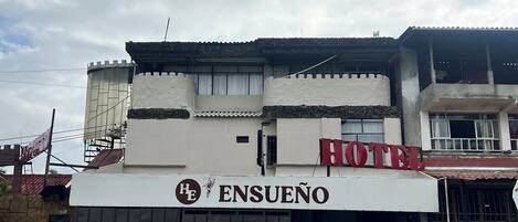 A hotel with a sign reading "ENSUENO HOTEL" and a logo above the name.