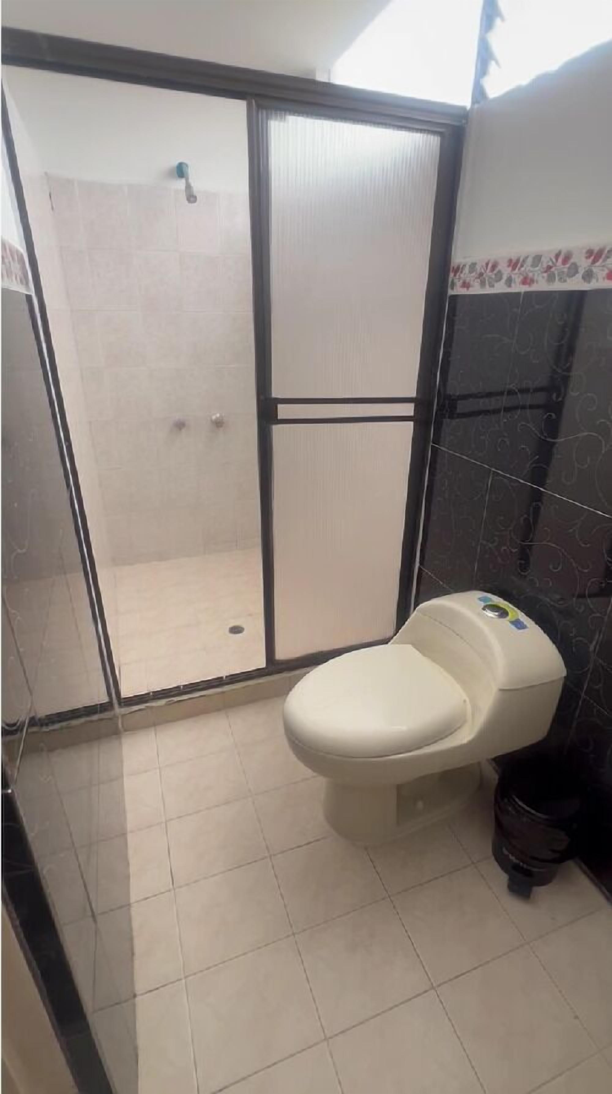 Ein Badezimmer mit Duschkabine, Toilette und Mülleimer.