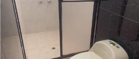 Ein Badezimmer mit Duschkabine, Toilette und Mülleimer.